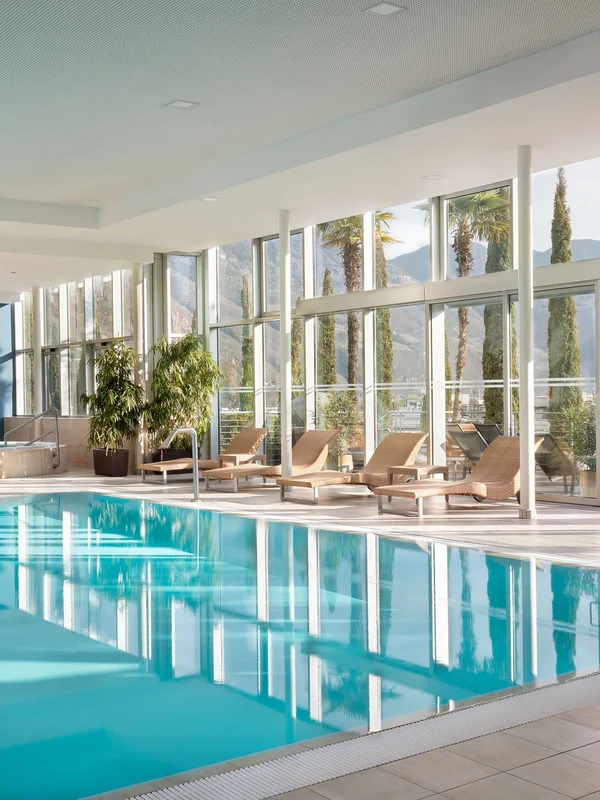 Piscina interna moderna con grandi finestre e lettini a bordo