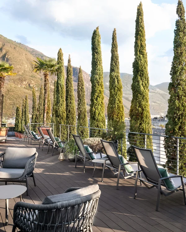 Terrazza con sedie e alberi alti vicino a una montagna