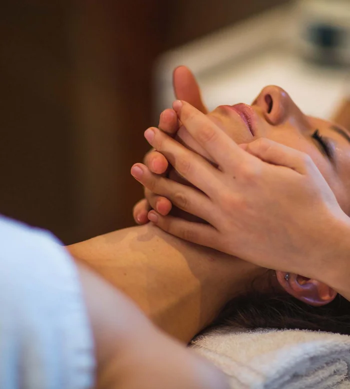 Massaggio rilassante del viso in spa con asciugamano arrotolato