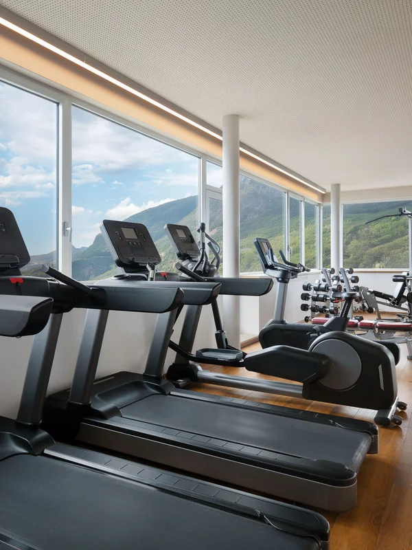 Modernes Fitnessstudio mit Geräten und großen Fenstern mit Bergblick