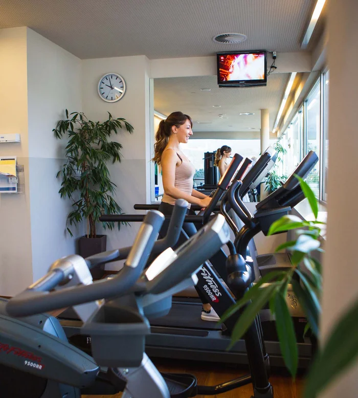 Donna che corre sul tapis roulant in palestra moderna illuminata